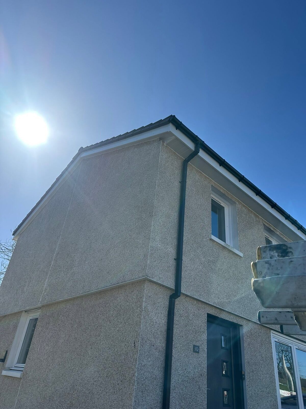 New white bargeboard, fascia and soffit with a black gutter and downpipe at the front corner