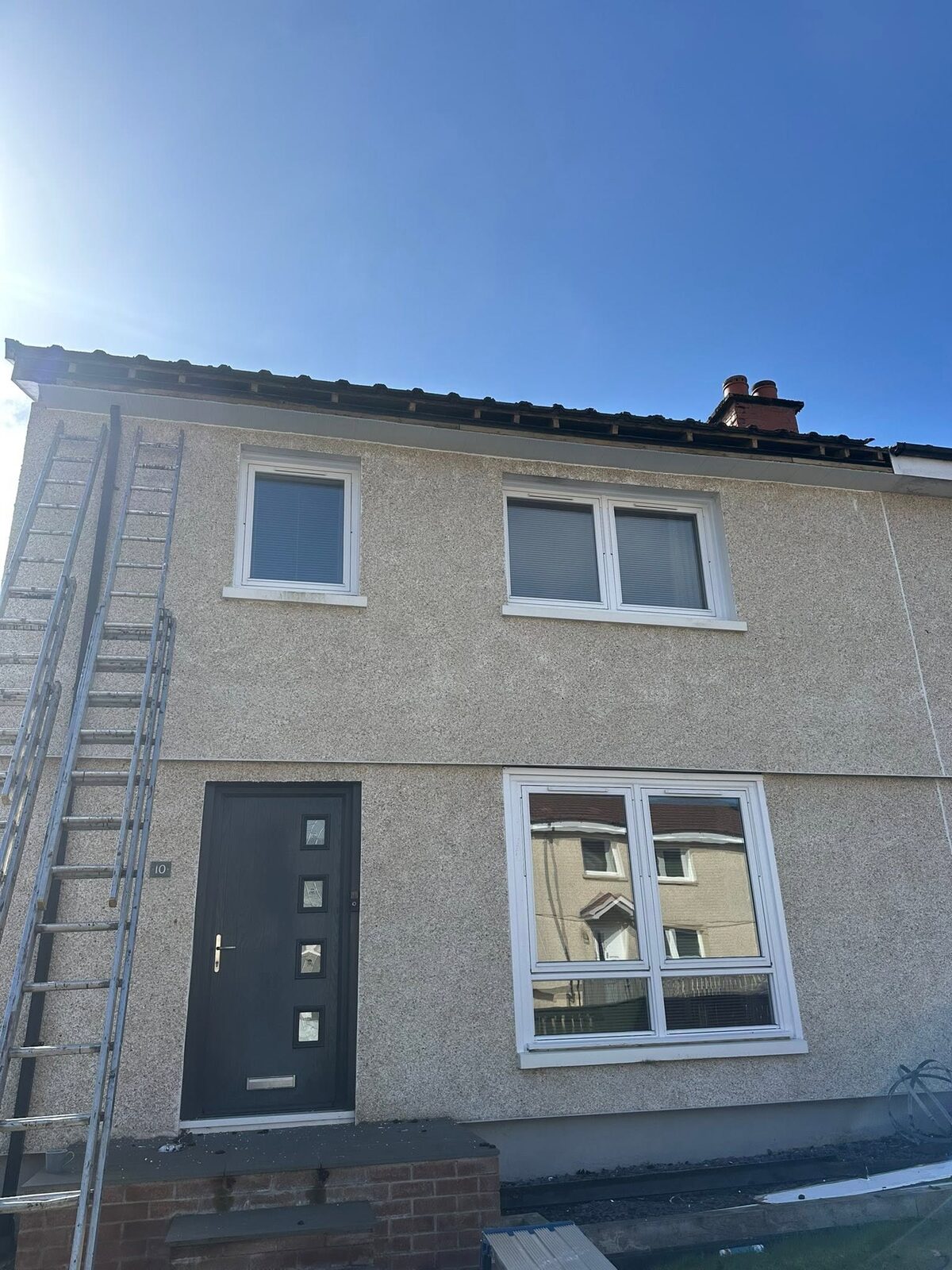 Front of a pebbledash house with the old fascia and gutter off, showing the rafter ends
