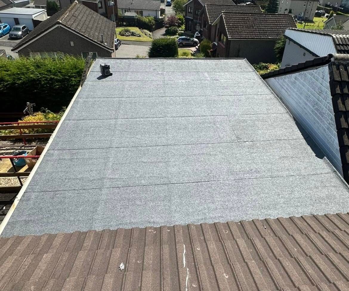 Finished flat roof in grey mineral felt, seen from the tiled roof above