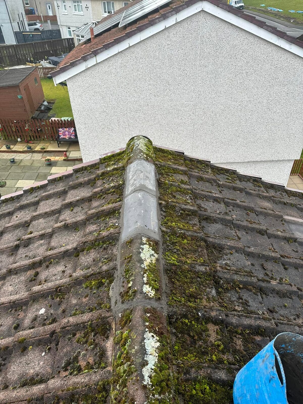 The same ridge with two new grey ridge tiles bedded and pointed in